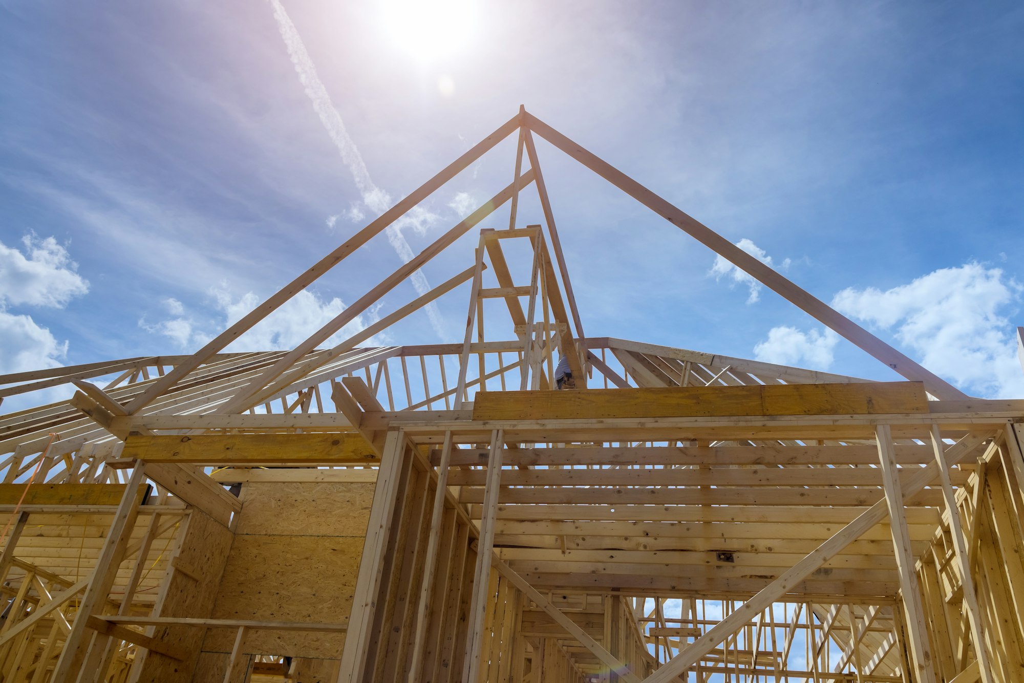 Aerial top view of construction working on the roof beams of under construction wooden built home