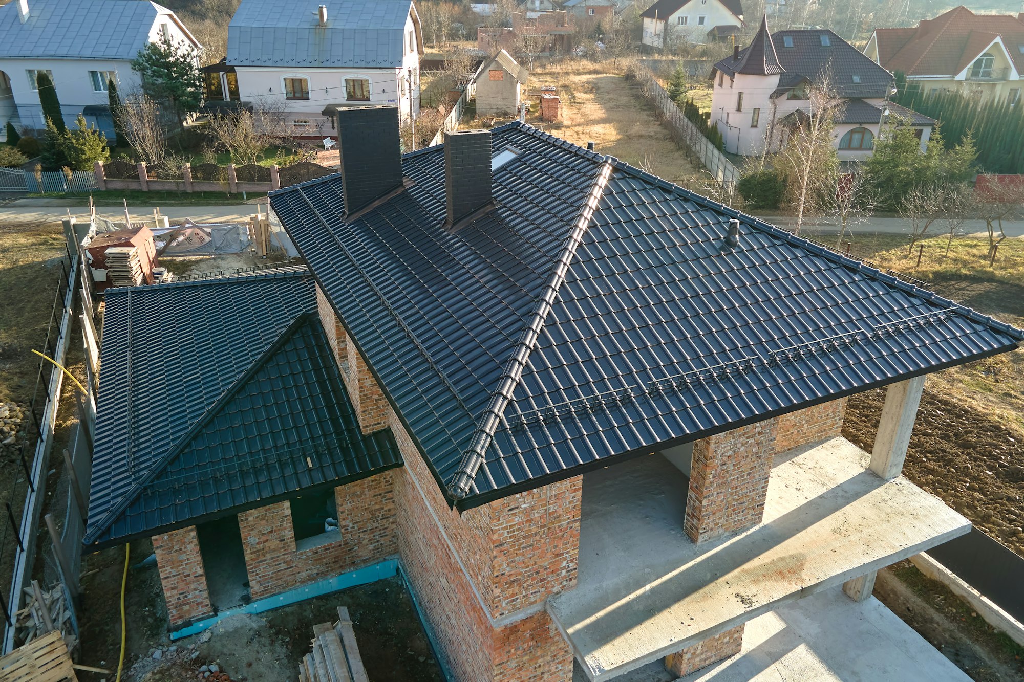 Aerial view of house roof top covered with ceramic shingles. Tiled covering of building under