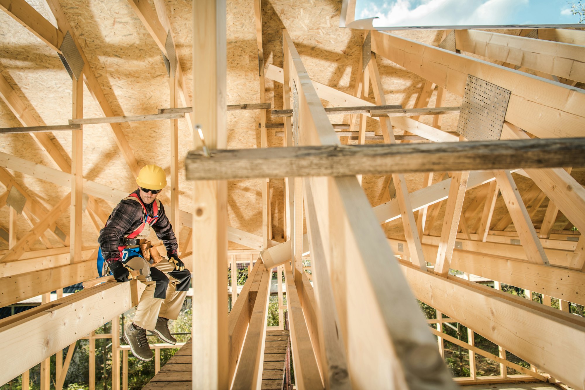 Construction Worker Sitting on a Wooden Roof Beam