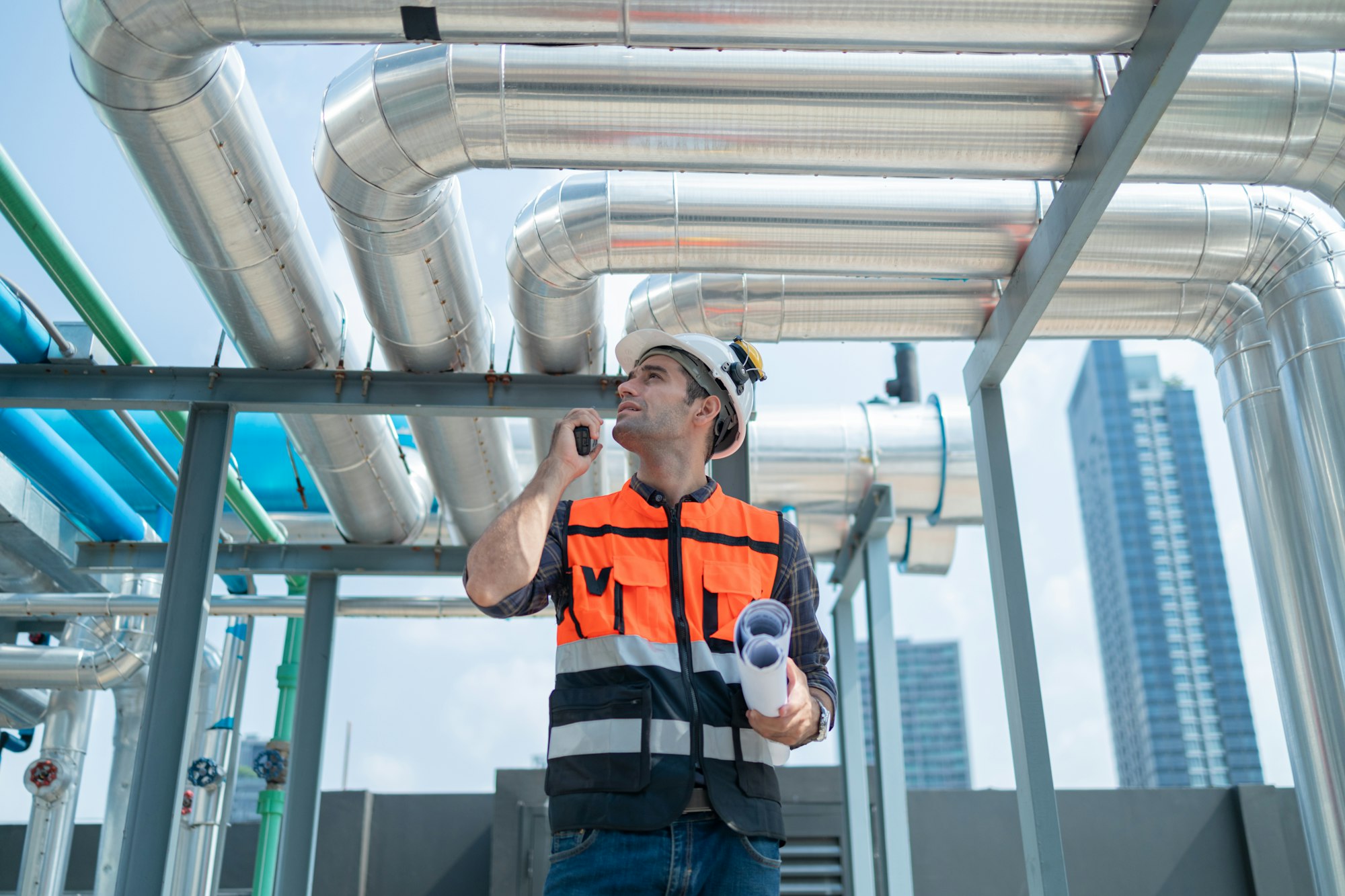 Engineer Inspecting Industrial Pipes on Rooftop